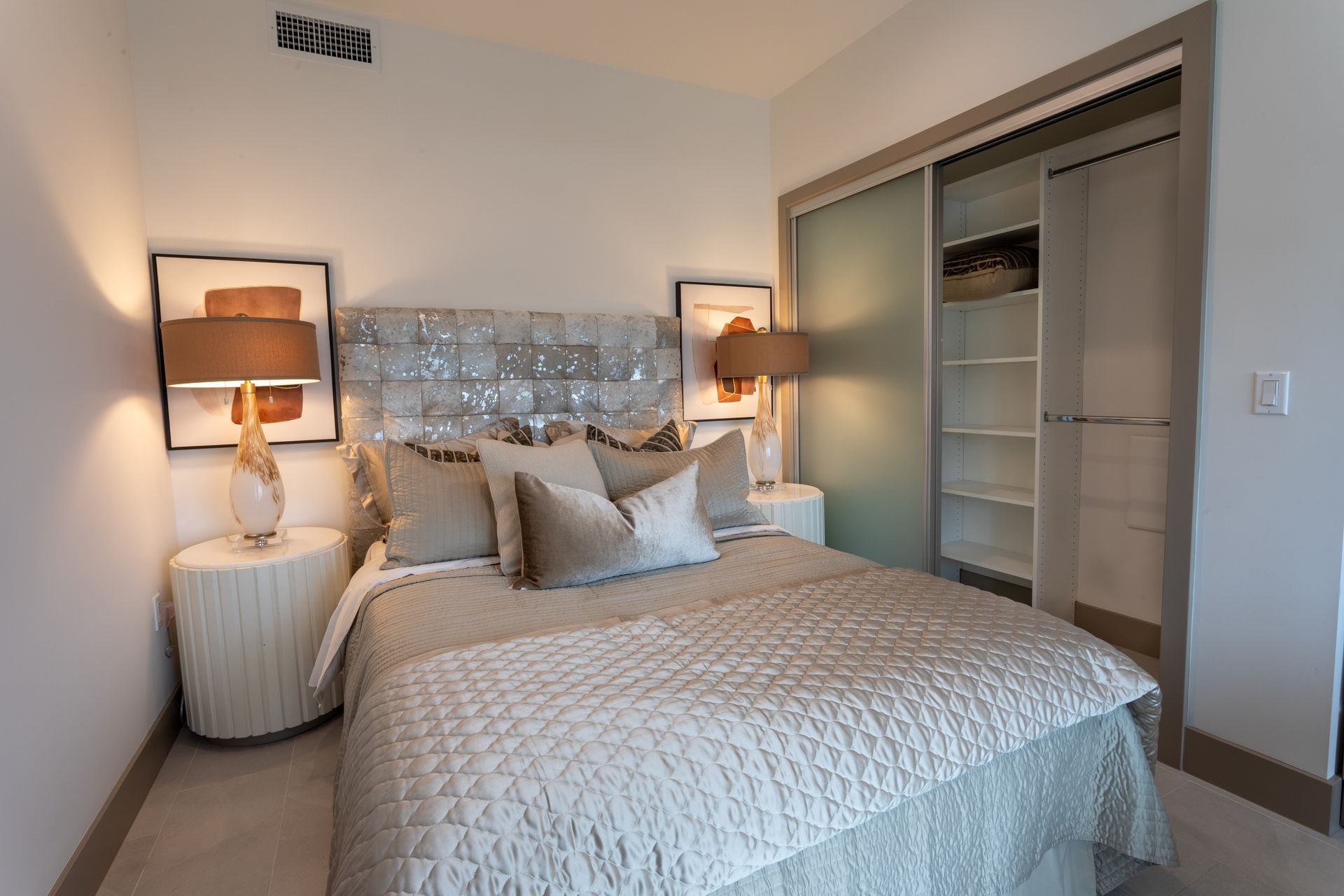 Bedroom with a bed, nightstands, lamps, artwork, and a closet with sliding doors.