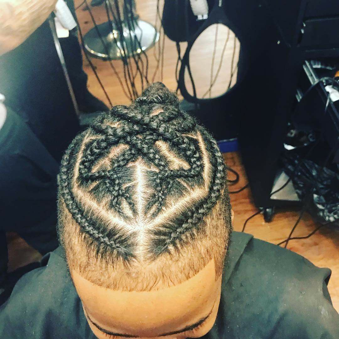 A man is getting his hair braided in a geometric pattern