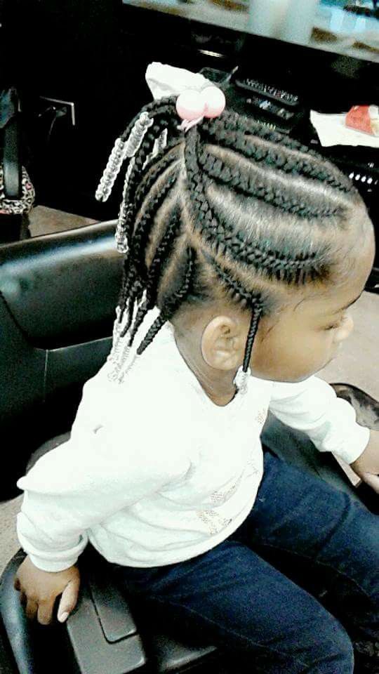 Girl with braided hairstyle, wearing a white shirt and jeans, sitting in a salon chair.