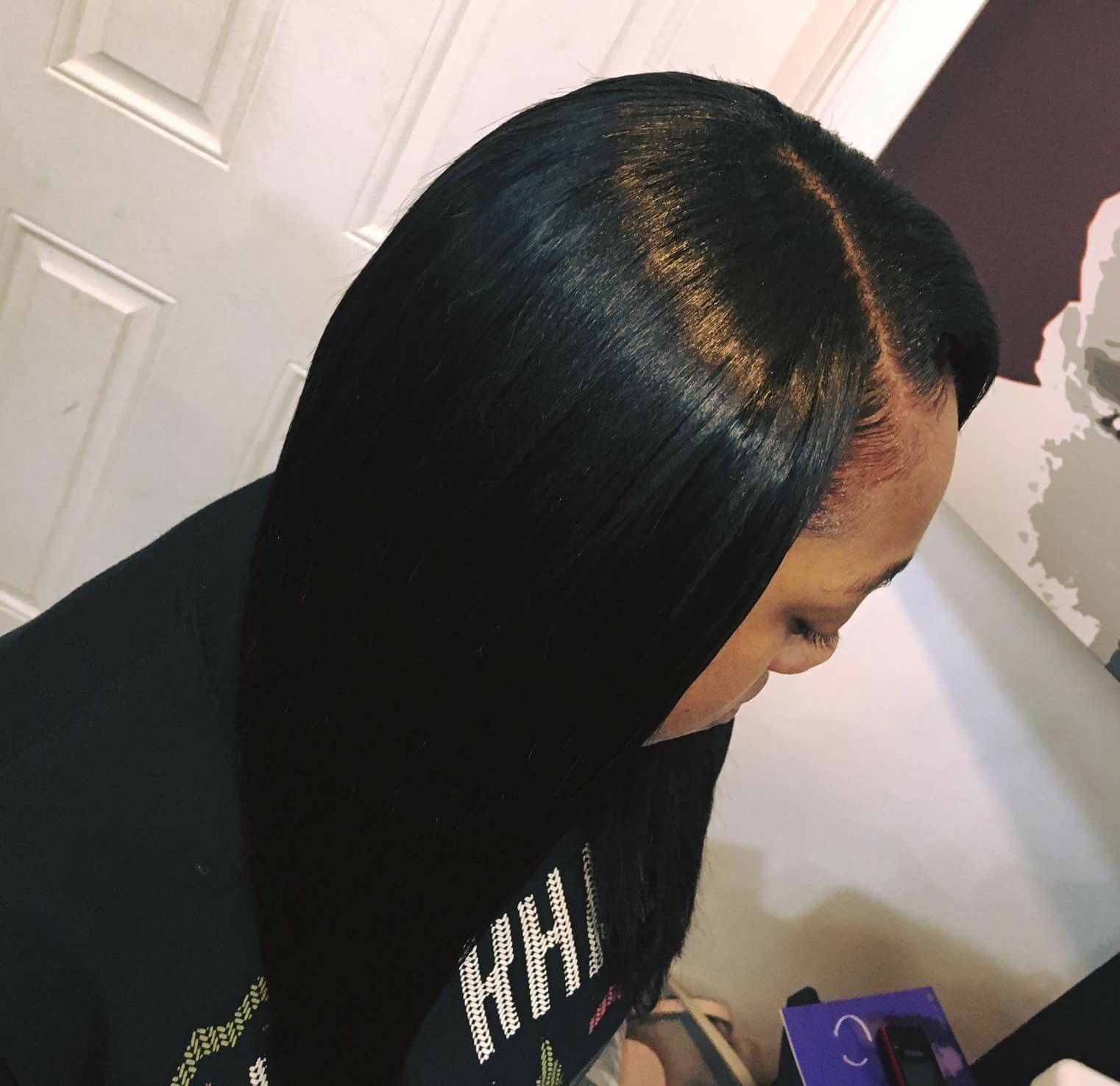 Woman with sleek black, straight hair; side part, light skin, indoors.