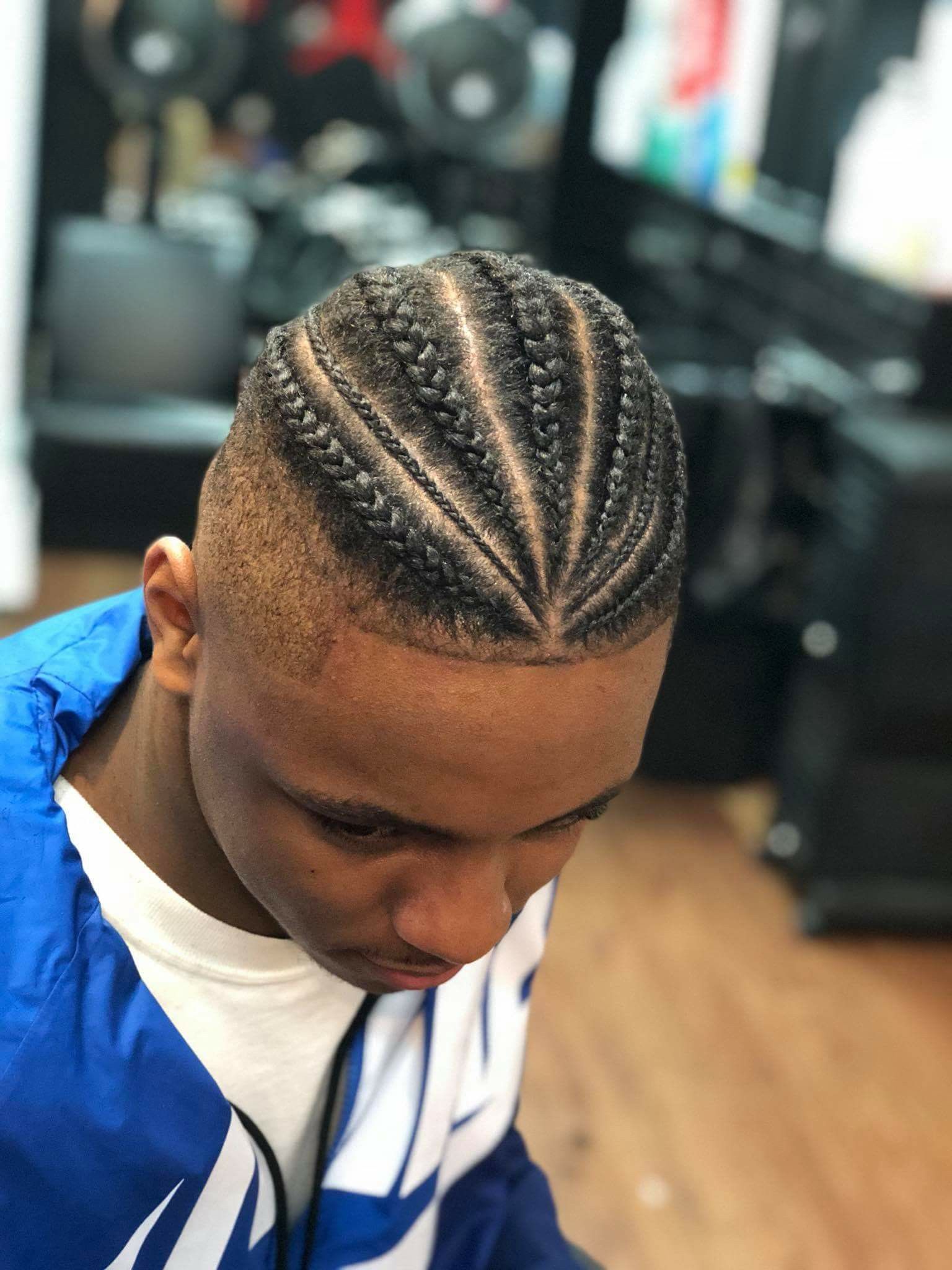 A young man with a fade haircut and cornrow braids, wearing a blue and white jacket.