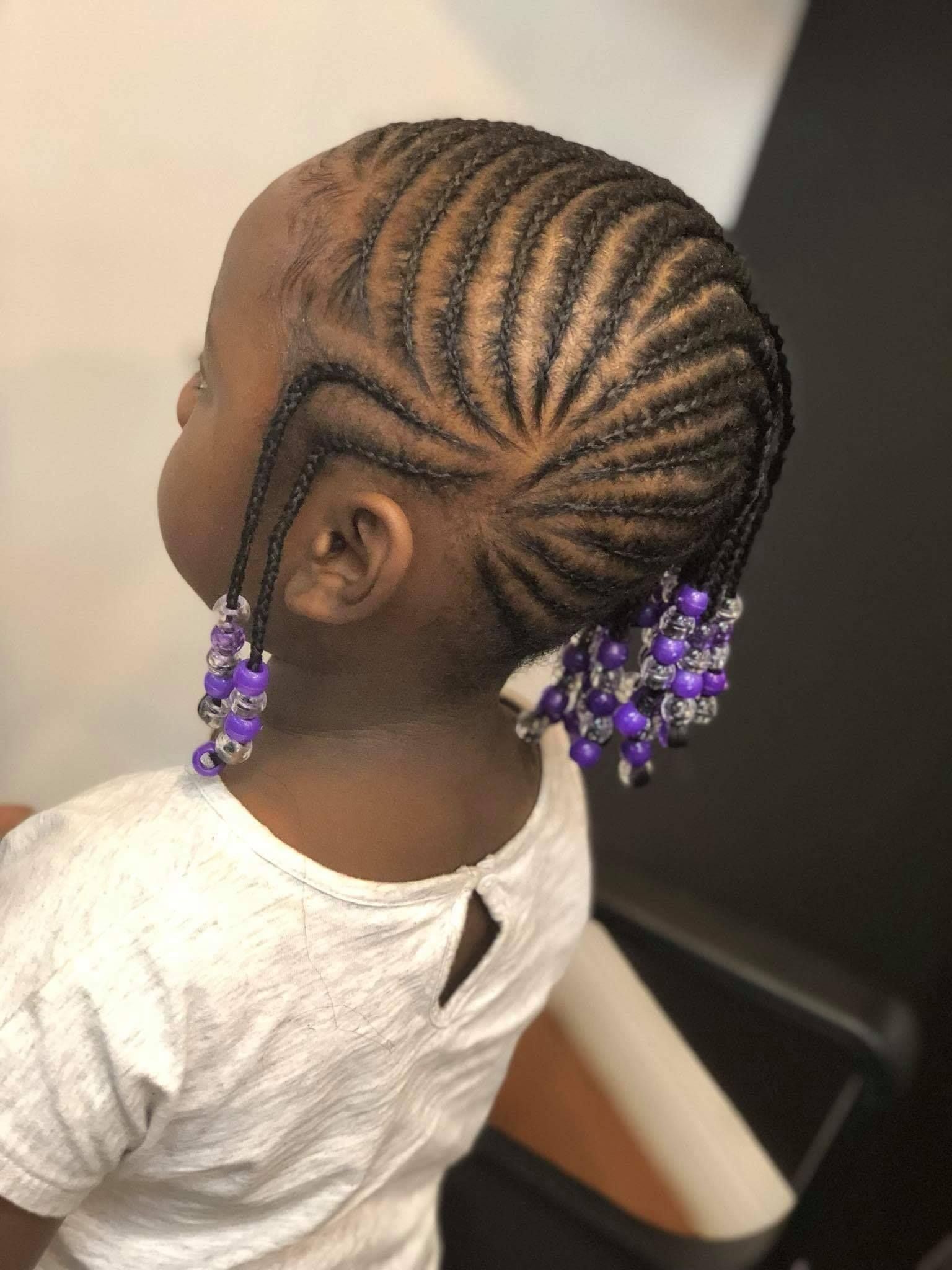 A little girl with braids and purple beads in her hair.