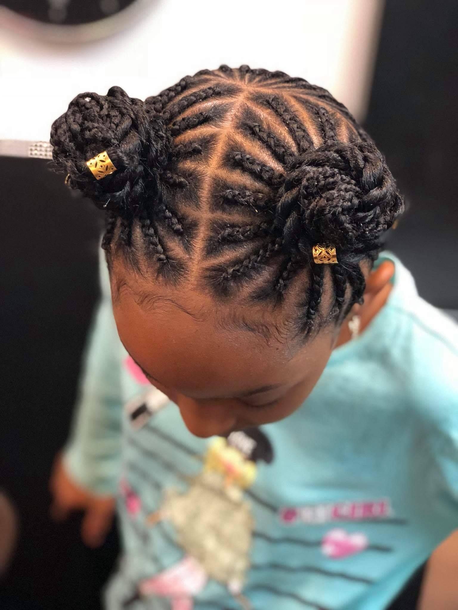 Young Black girl with braided space buns, wearing a blue shirt.