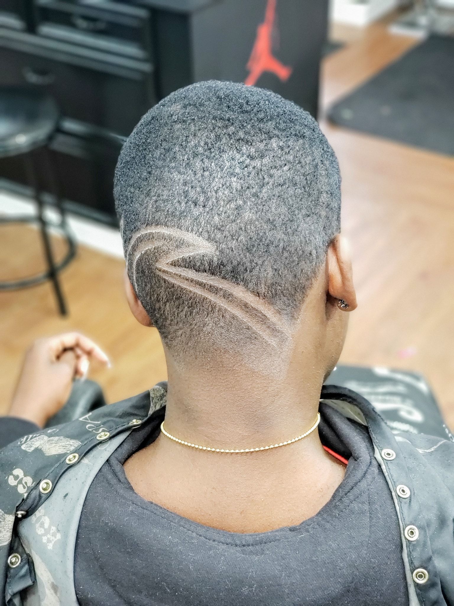 A woman is getting her hair cut at a barber shop.