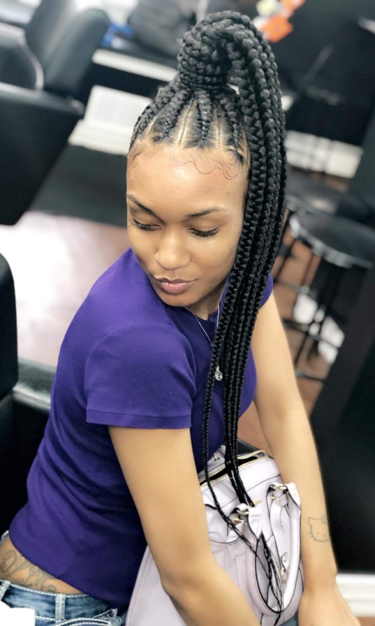 Woman with braided ponytail wearing a purple shirt in a salon.