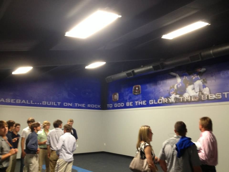 A group of people standing in front of a wall that says baseball built on the rock