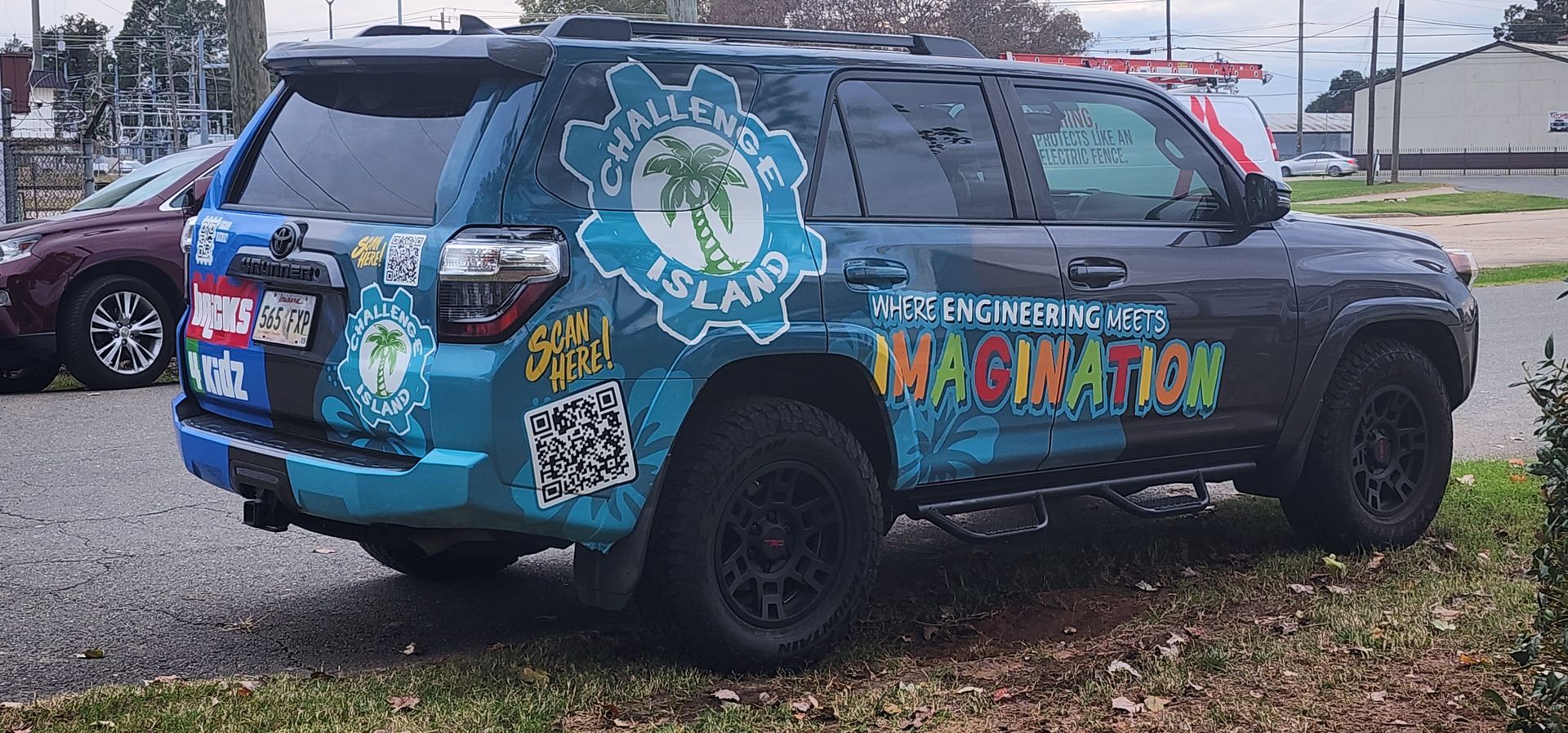 A blue suv with a lot of stickers on it is parked in a parking lot.