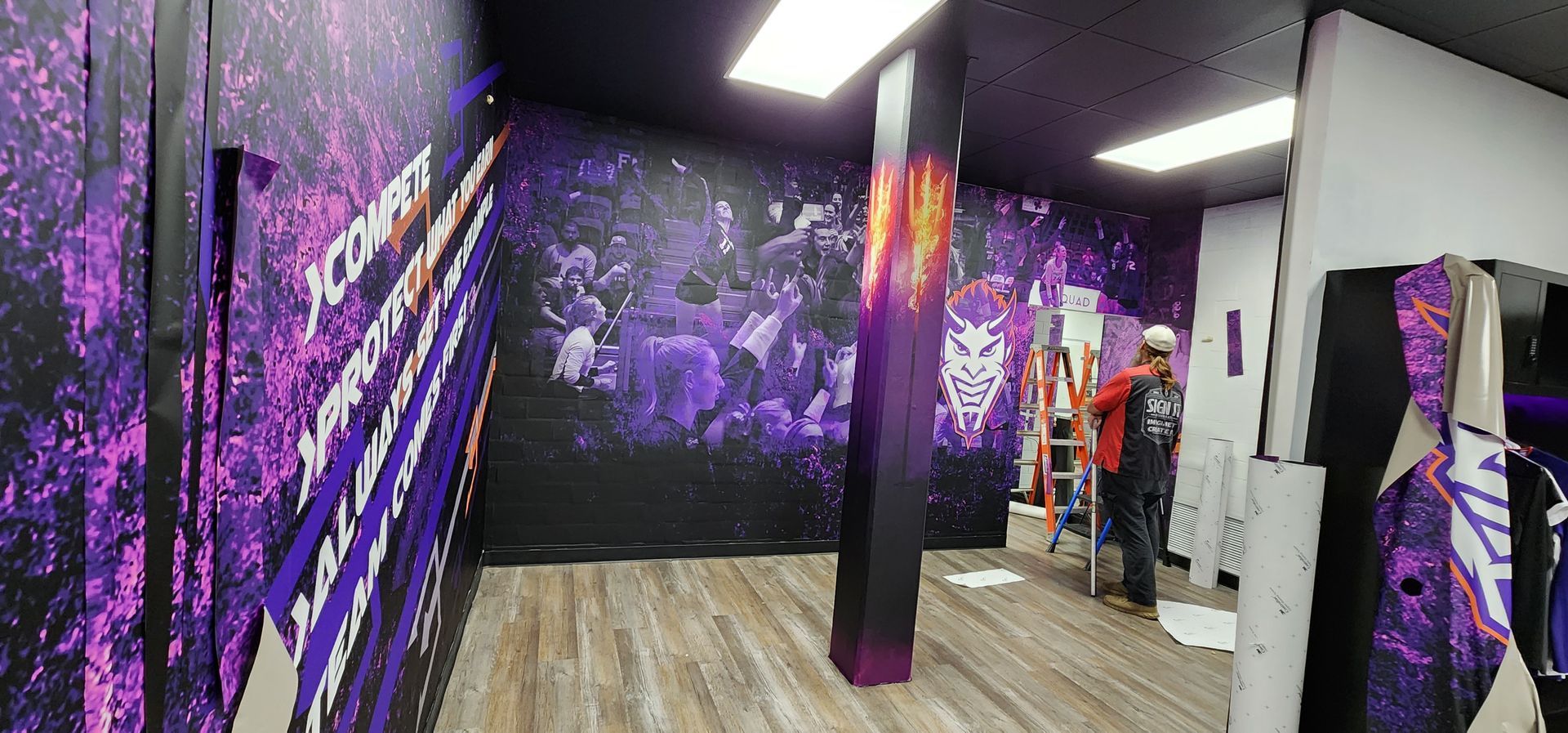 A man is standing on a ladder in a room with purple walls.