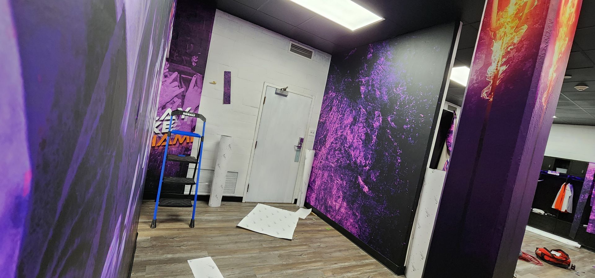 A hallway with purple and black walls and a ladder.