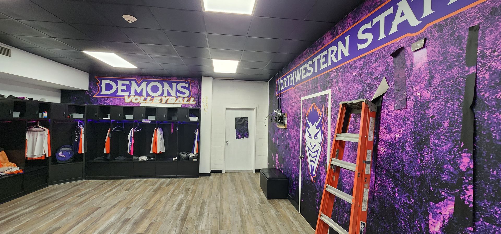 A locker room with a purple wall and a ladder.