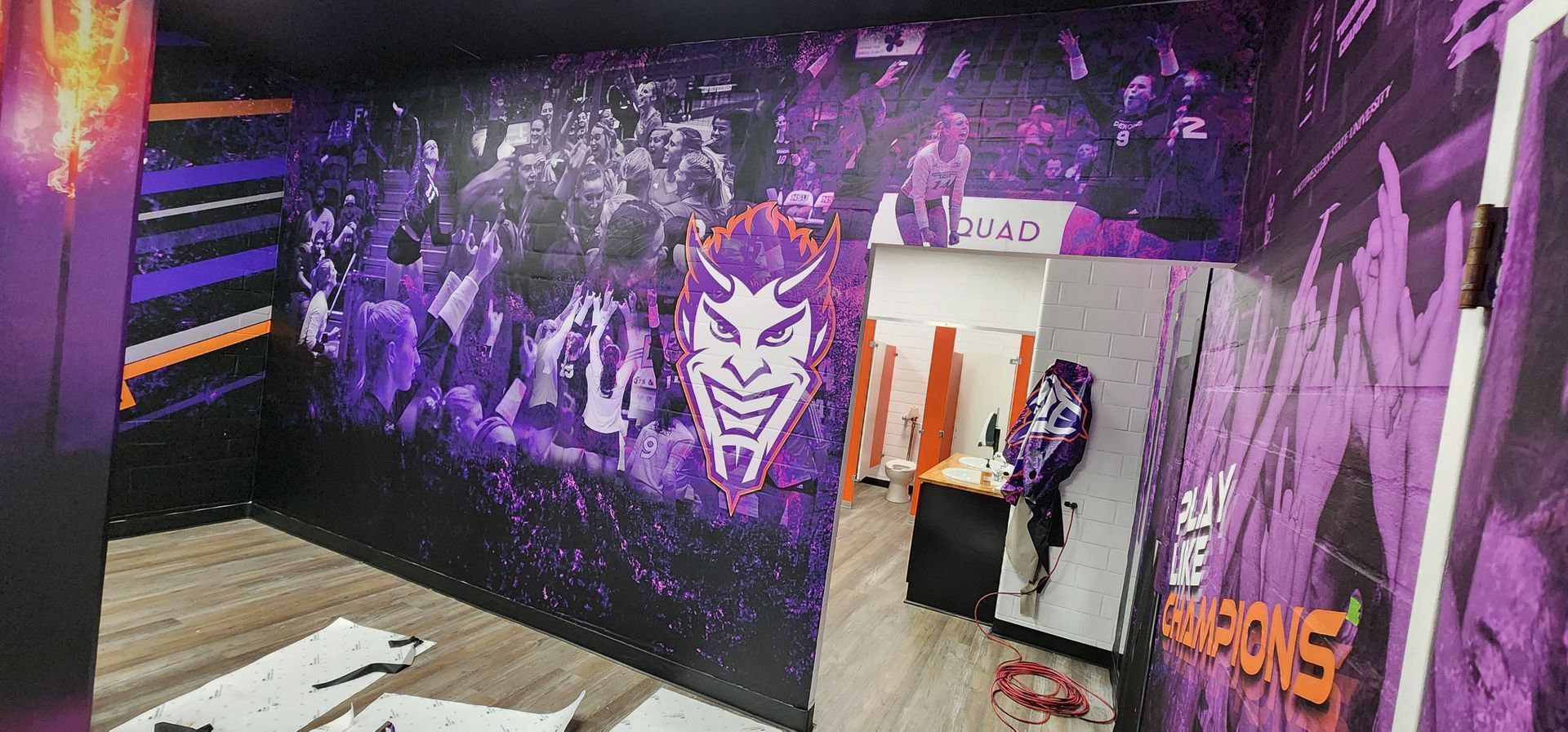 A room with purple and black walls and a joker mural on the wall.
