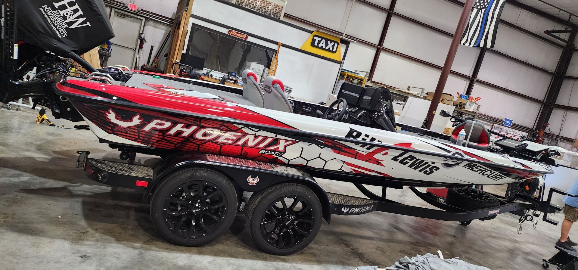 A red and white fishing boat is sitting on a trailer in a warehouse.