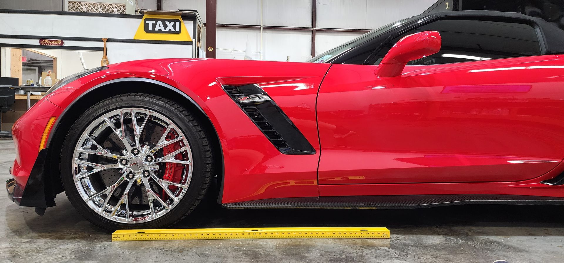 A red sports car is parked in a garage next to a taxi sign.