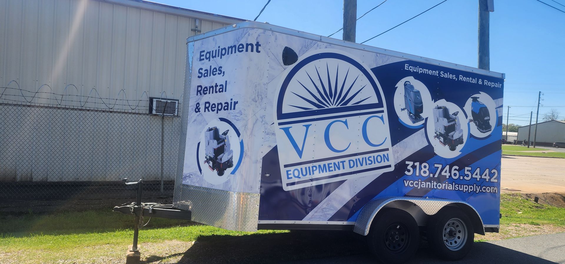 A trailer with the word vcc on it is parked in front of a building.