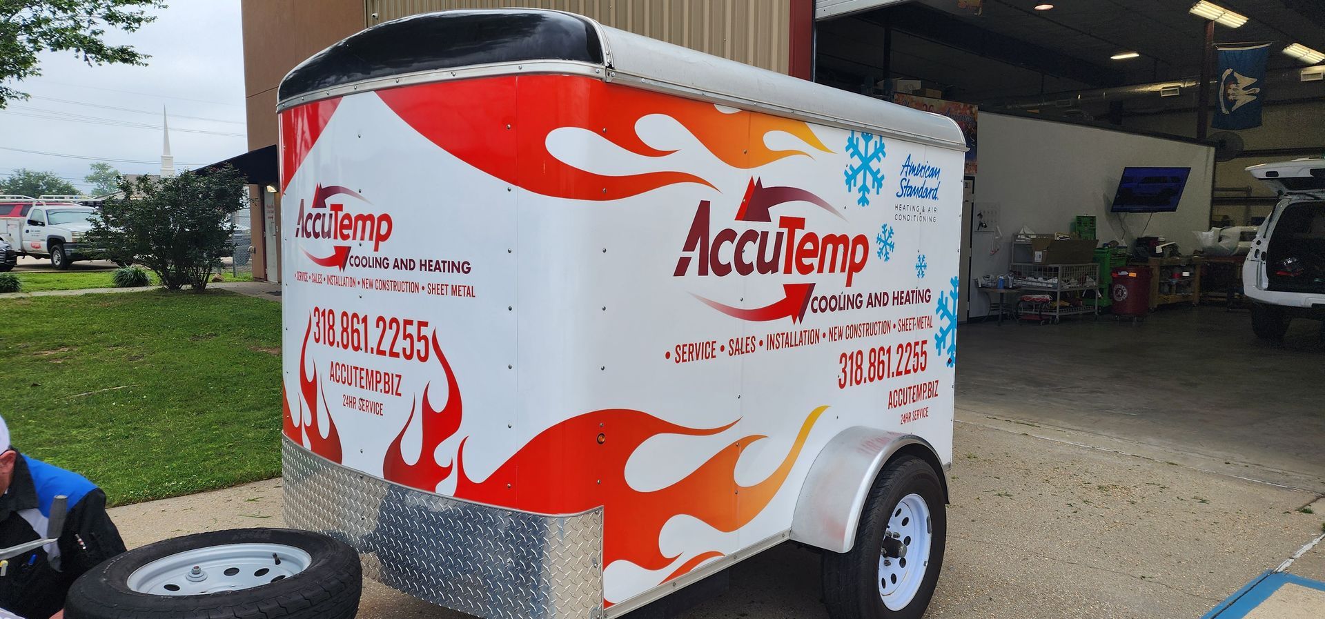 A white trailer with red flames on it is parked in front of a building.