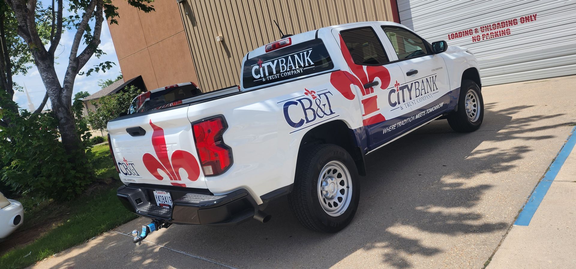 A white truck is parked in a parking lot in front of a building.