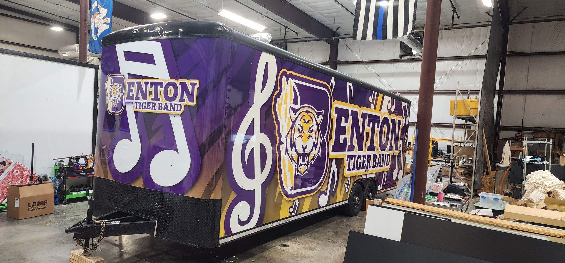 A purple trailer with a treble clef on it is in a garage.