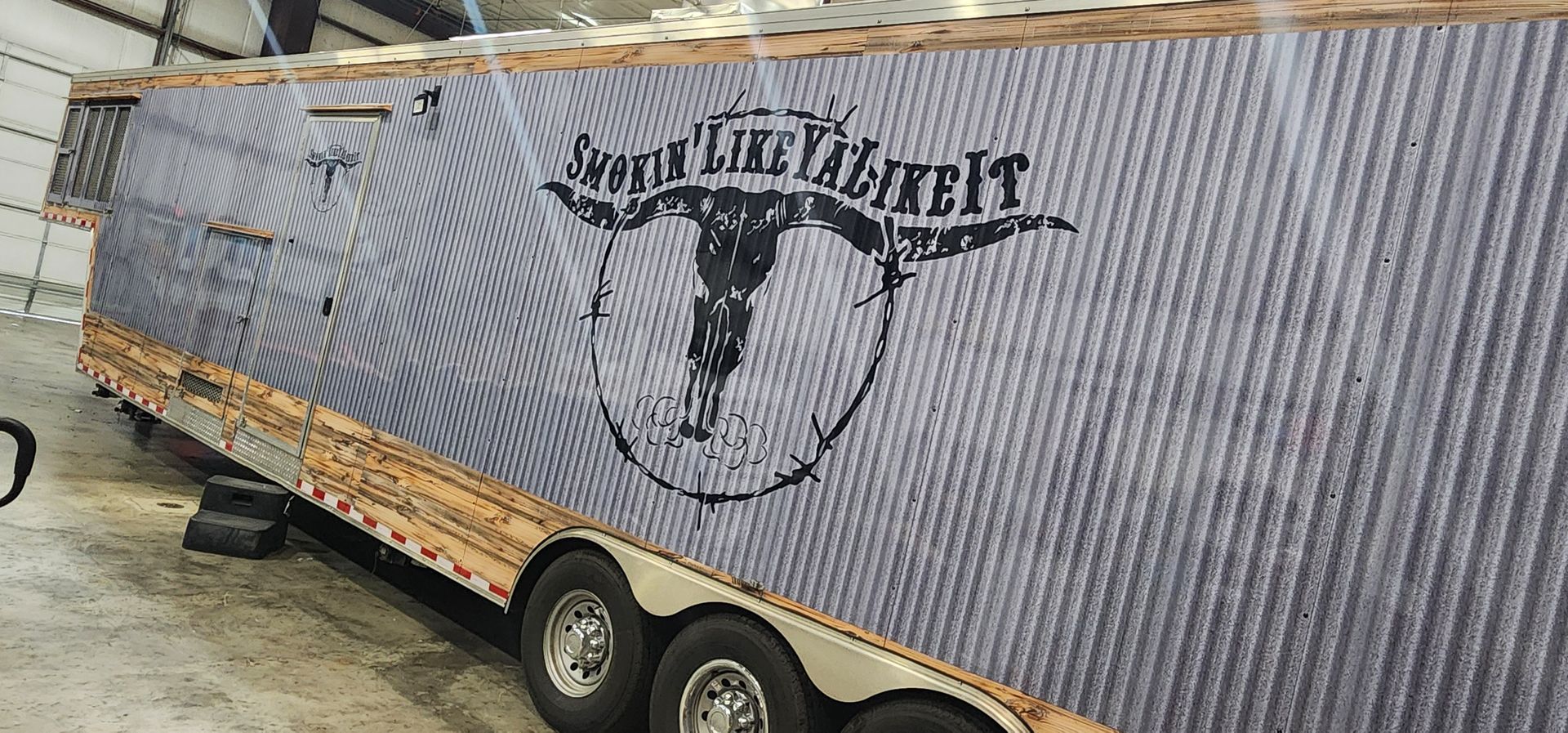 A trailer with a picture of a bull on it is parked in a garage.