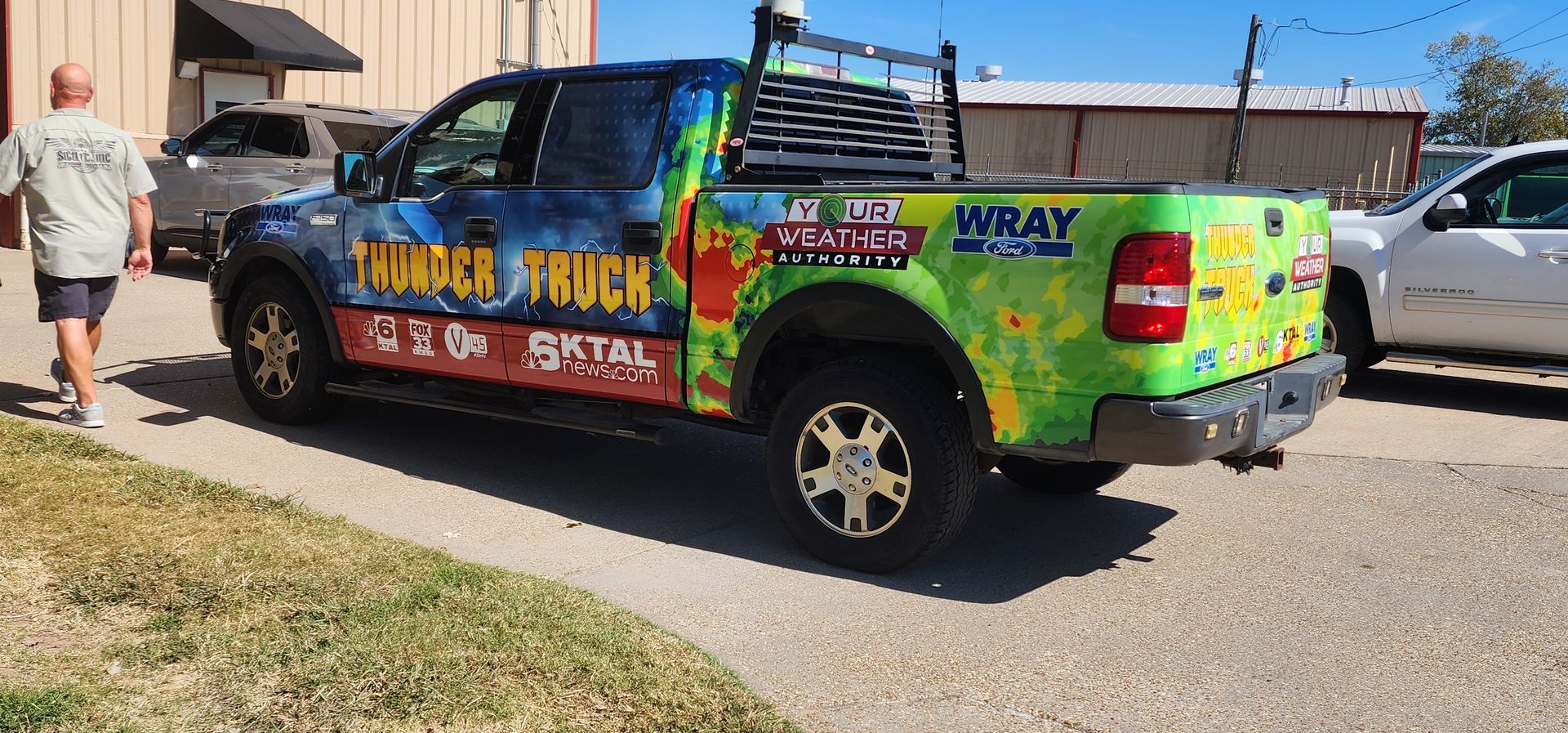 A man is walking past a colorful truck that says thunder truck.