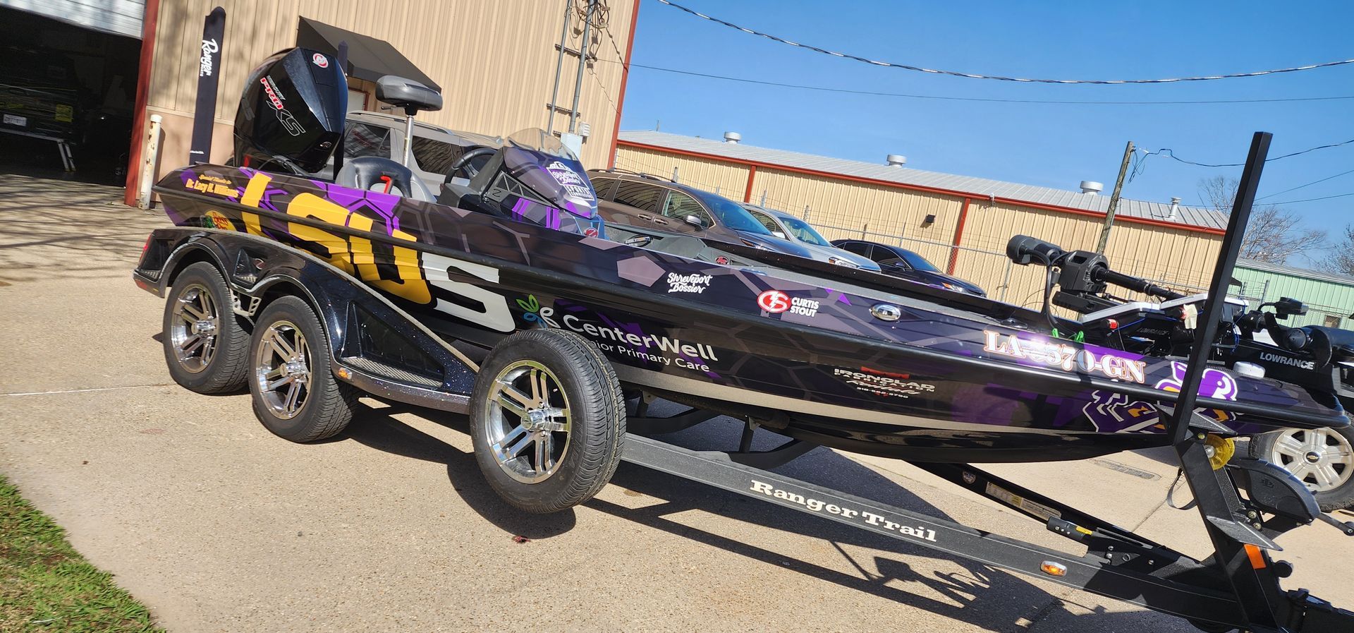 A purple and black fishing boat is parked on a trailer.