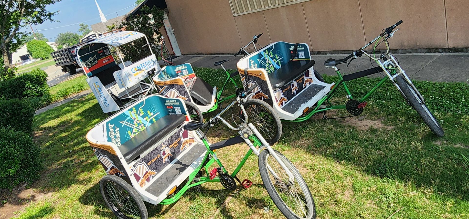 Three bicycles are parked in the grass in front of a building.