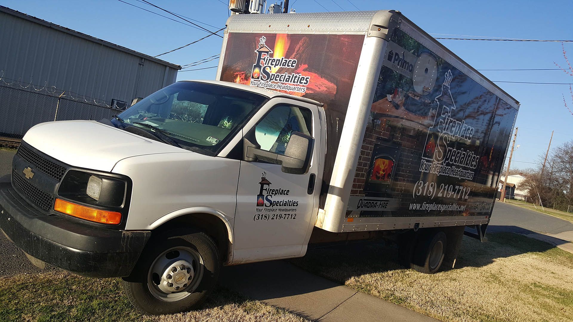 A white van with a pizza on the side is parked on the side of the road