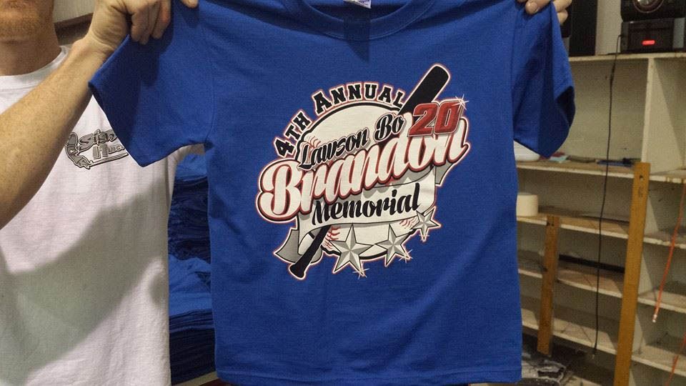 A man is holding a blue shirt that says brandon