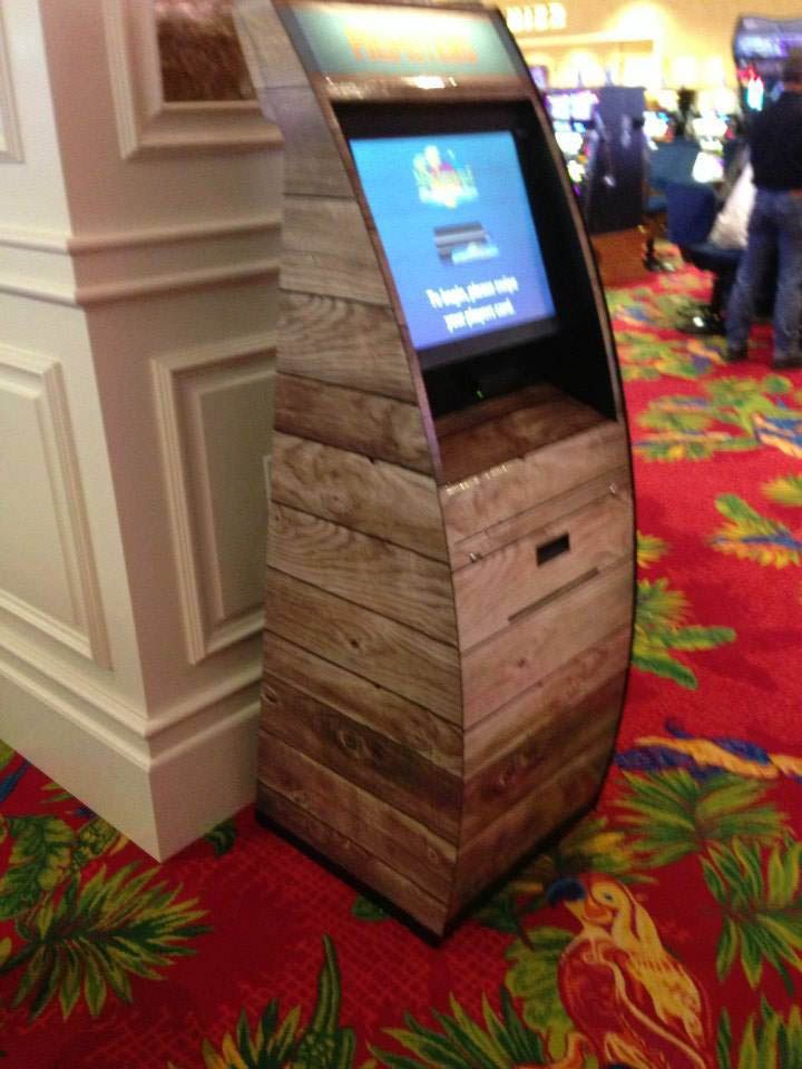 A wooden kiosk with a screen is sitting on a red carpet in a casino.