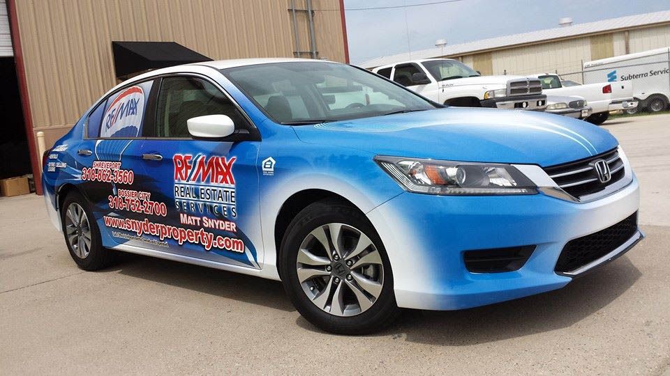 A blue and white honda accord is parked in front of a building