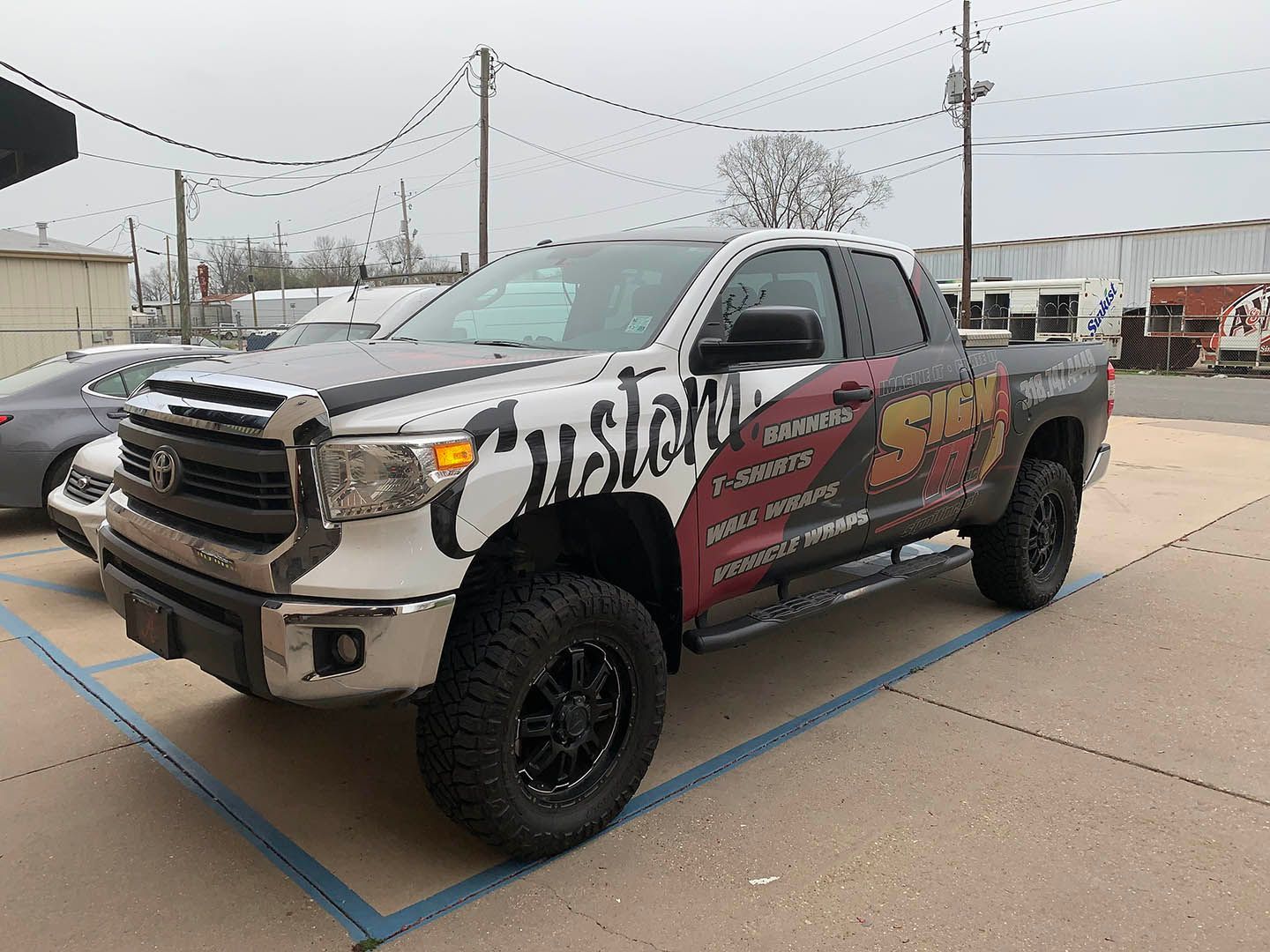 A truck with a wrap on it is parked in a parking lot.