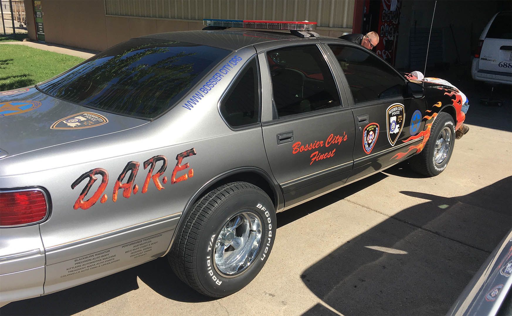 A silver car with the word dare on the side is parked in a driveway.