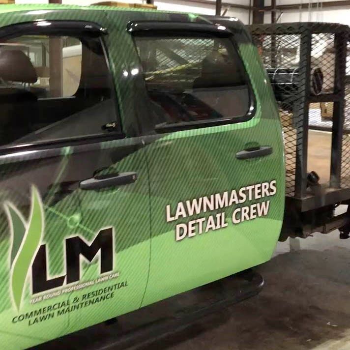 A green truck with lawnmasters detail crew written on the side