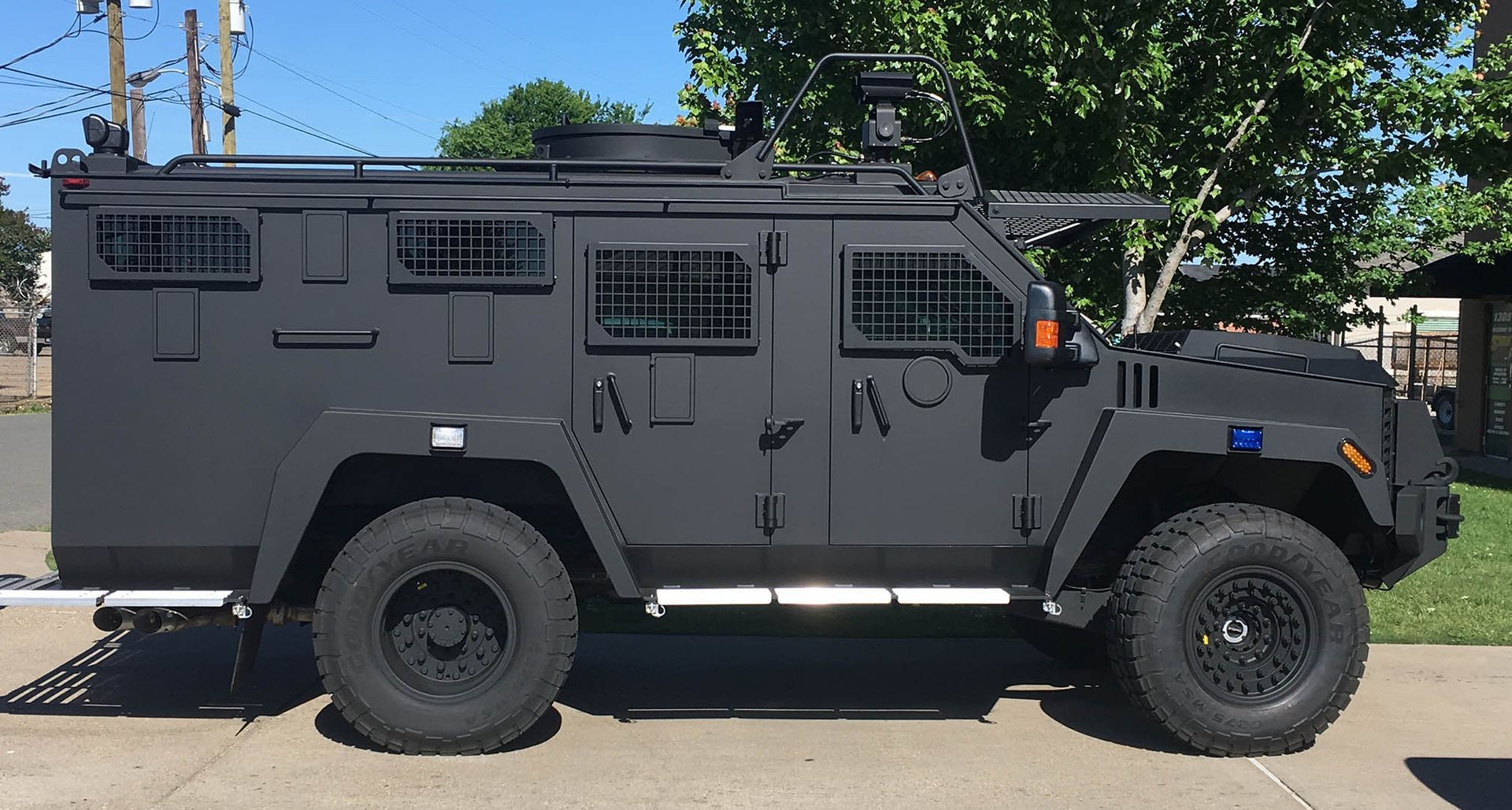 A black military vehicle is parked on the side of the road.