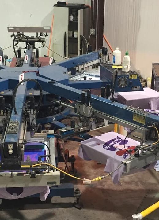 A machine that is printing t-shirts in a room