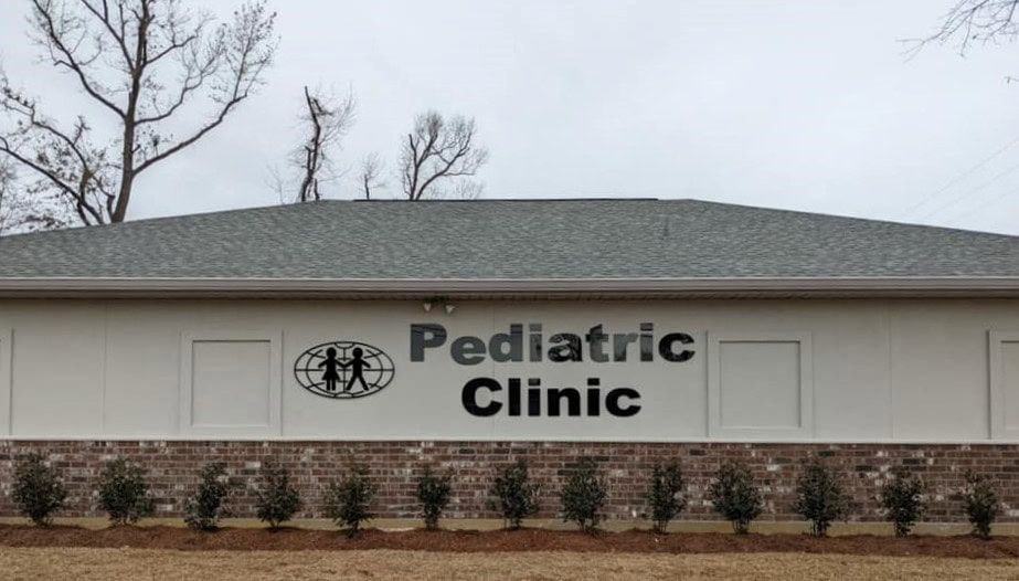 A white building with a sign that says pediatric clinic