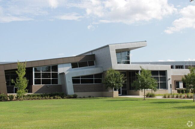 A large building with a lot of windows is sitting on top of a lush green field.