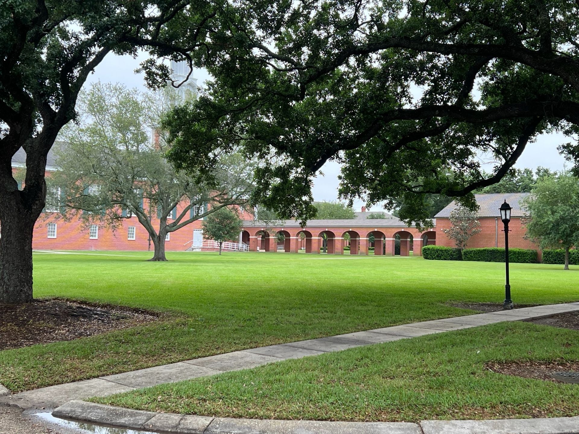 A large grassy field with a brick building in the background