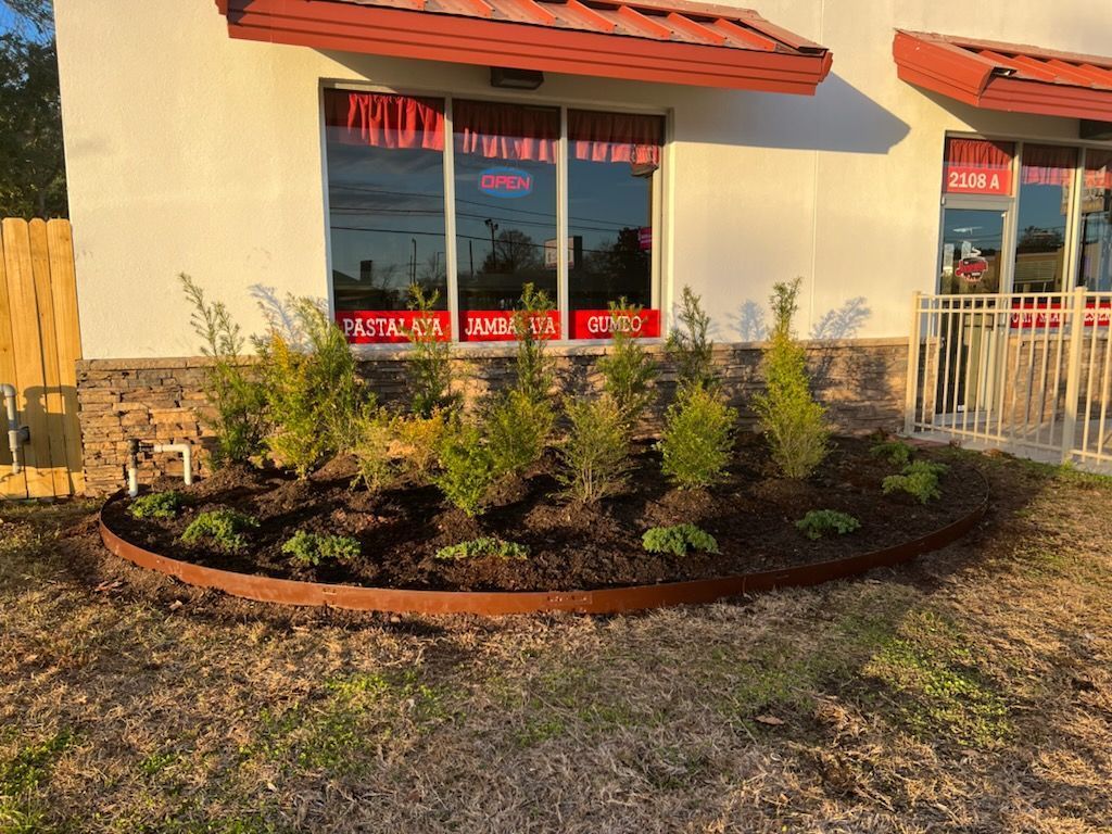 A white building with a red awning and a garden in front of it.