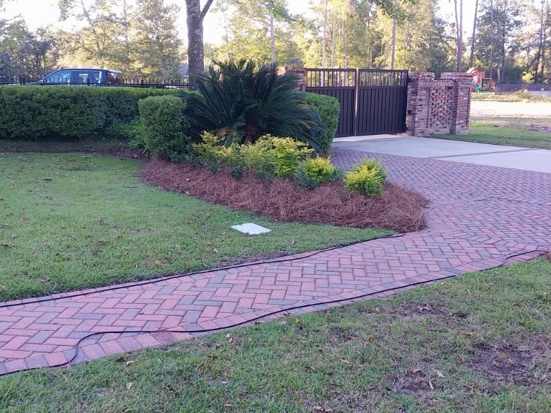 A brick walkway leading to a gate in a yard