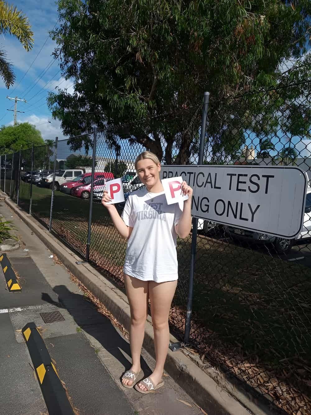 A Woman Is Standing In Front Of A Sign That Says Practical Test Parking Only — Solitude Driving School In Mooroobool, QLD