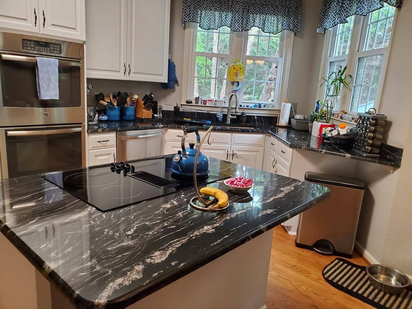 A kitchen with a black granite counter top and stainless steel appliances.
