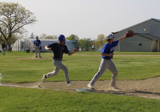 Two boys are playing baseball on a field with one wearing a blue jersey