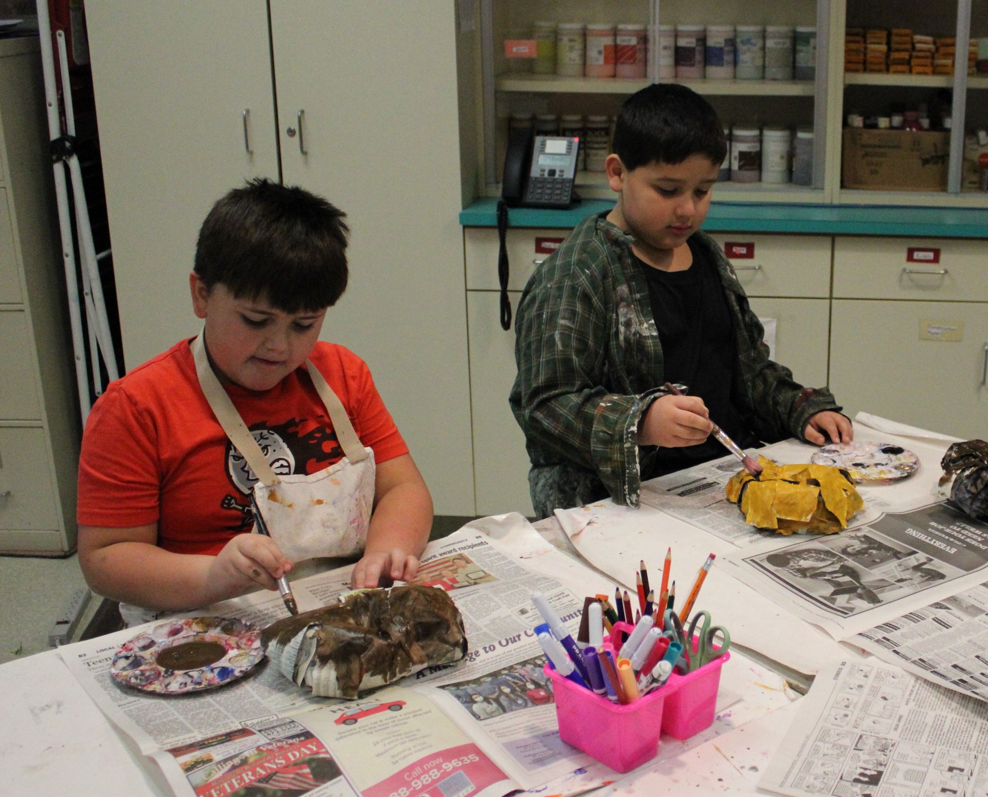 Two boys are sitting at a table with a newspaper on it that says ' washington post ' on it