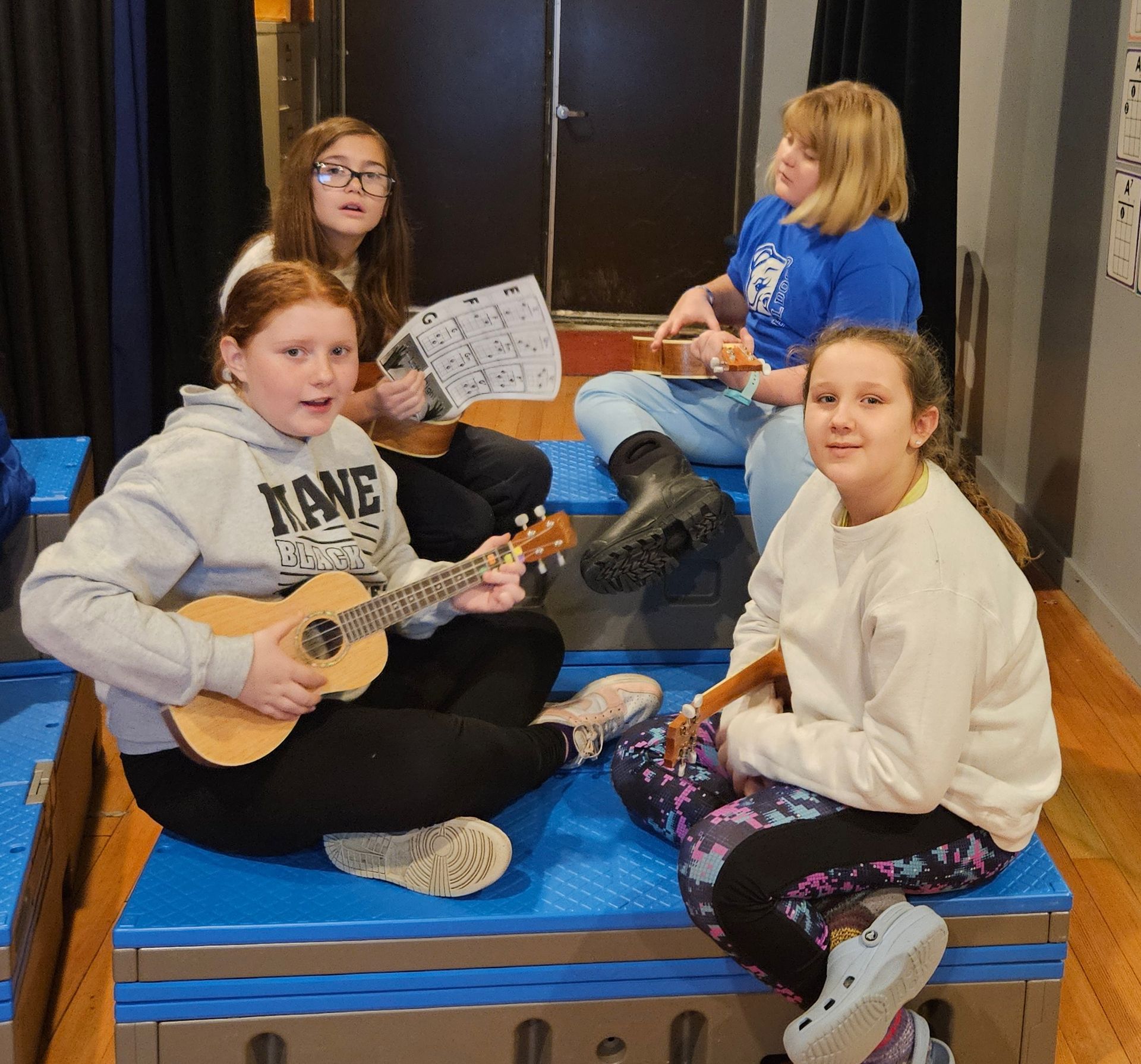 A girl in a kane sweatshirt is playing a guitar