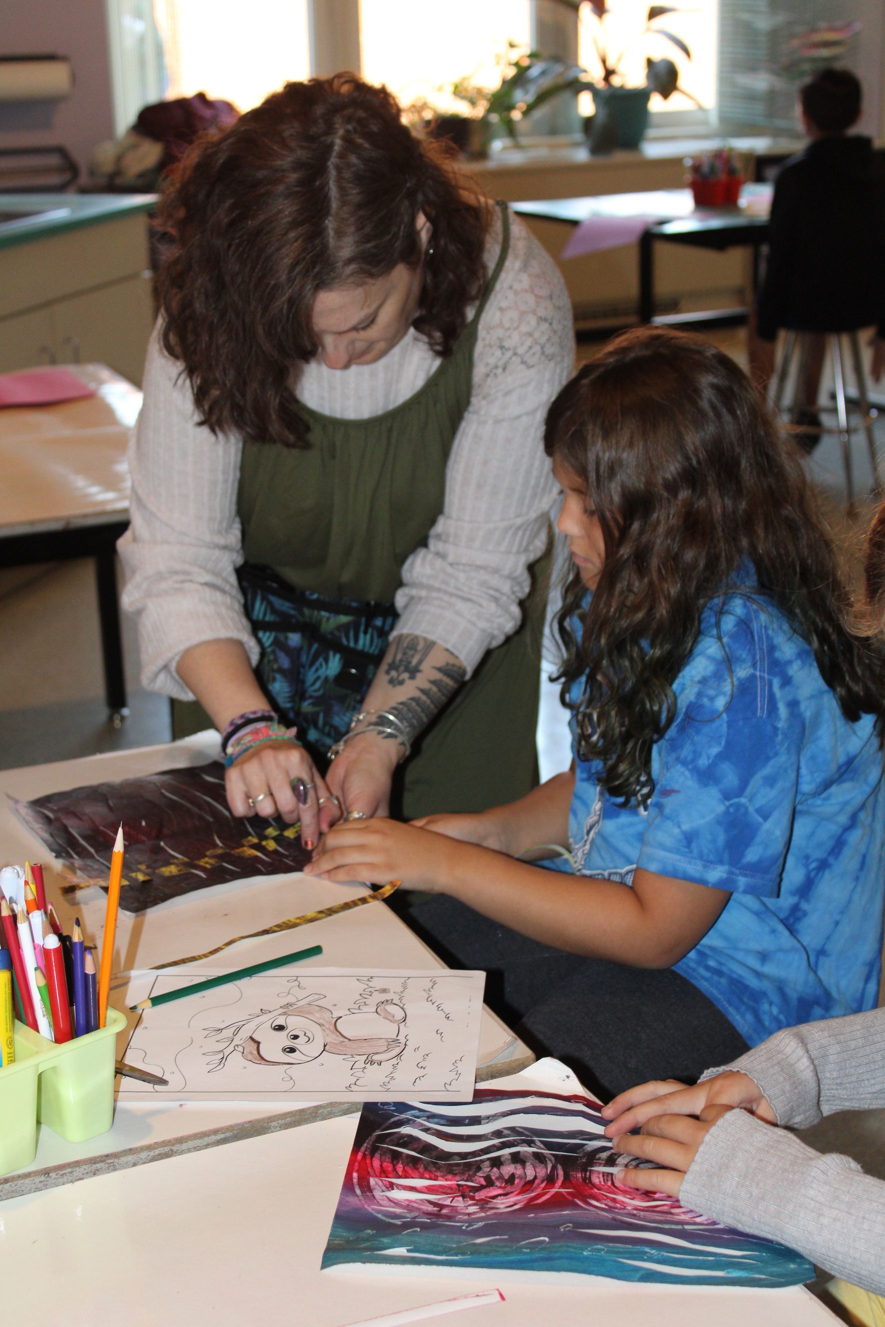 A woman is helping a young girl with a painting