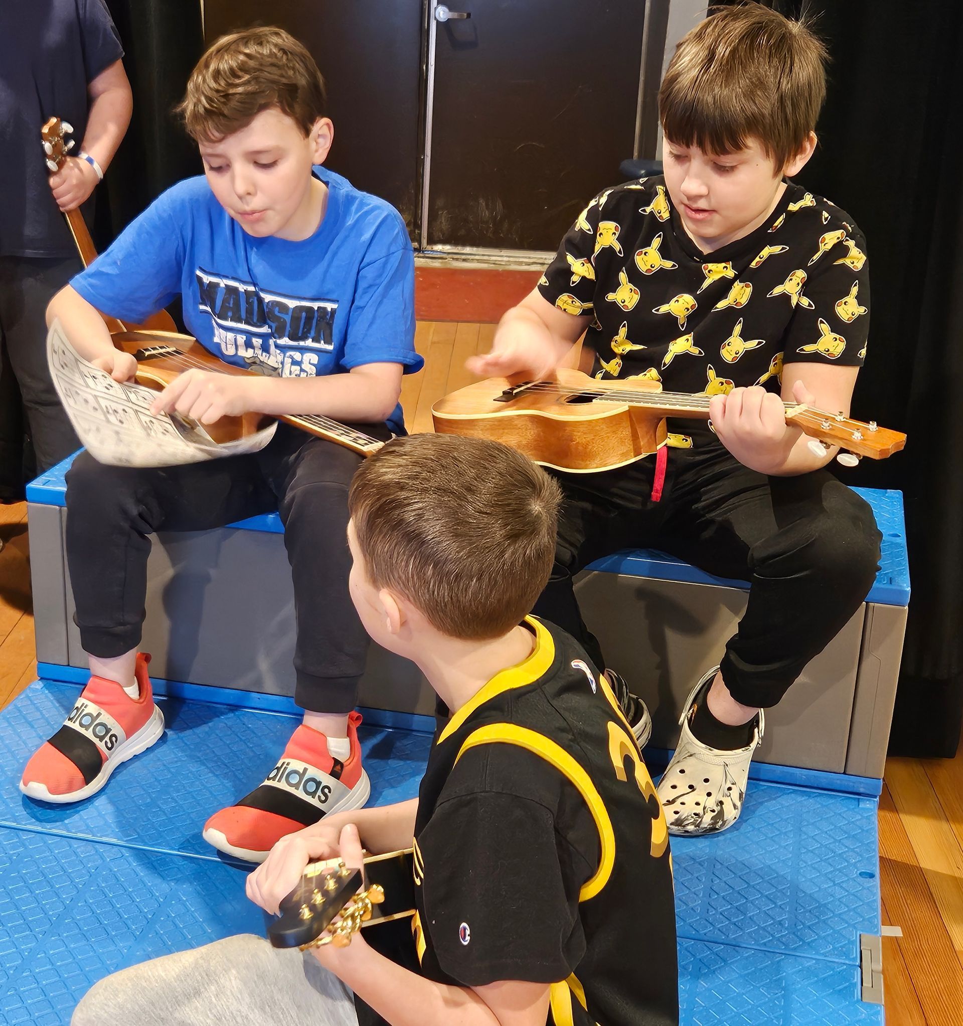 A boy in a madison shirt is playing a guitar