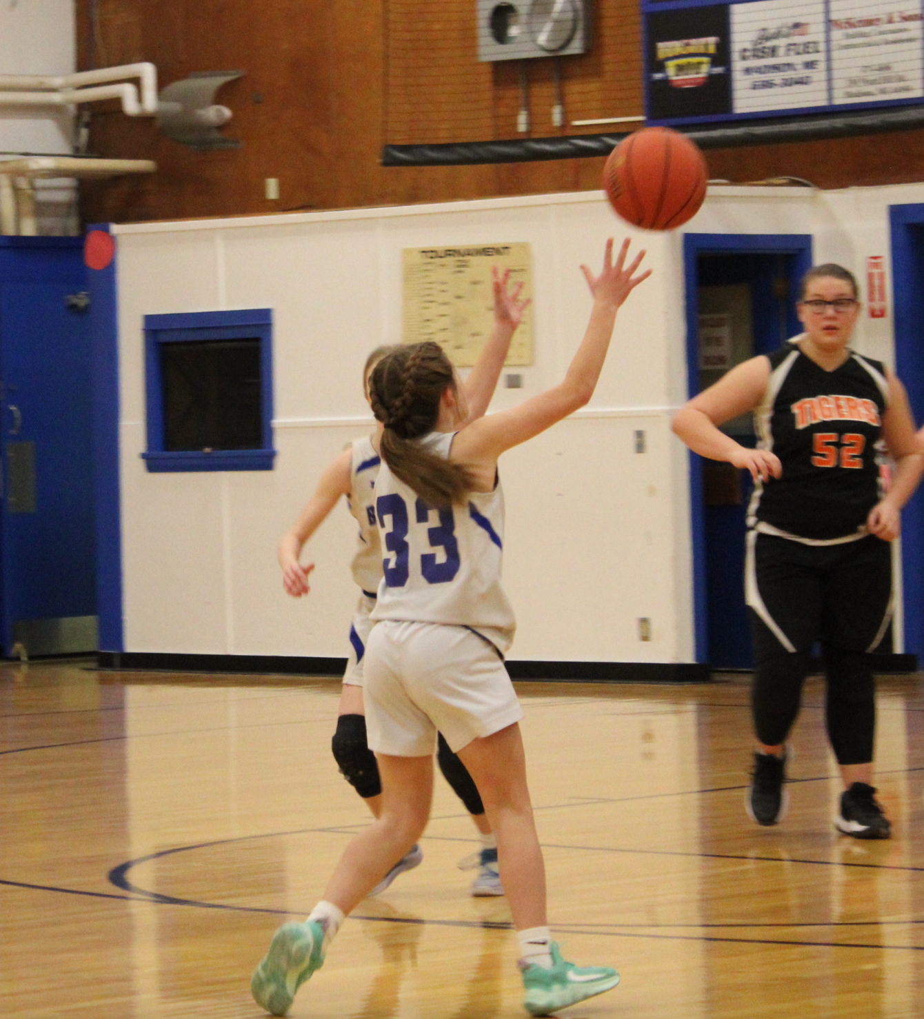 A girl with the number 33 on her jersey throws a basketball