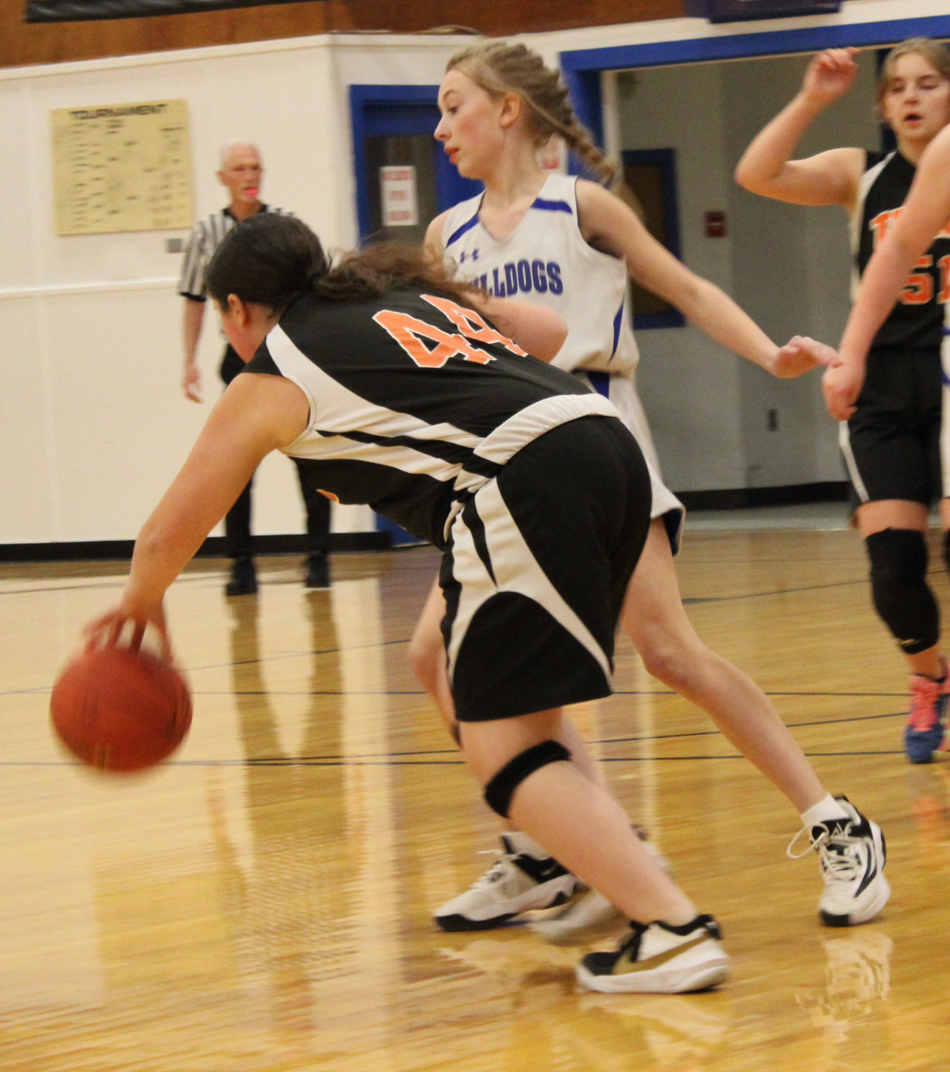 A female basketball player wearing number 44 dribbles the ball