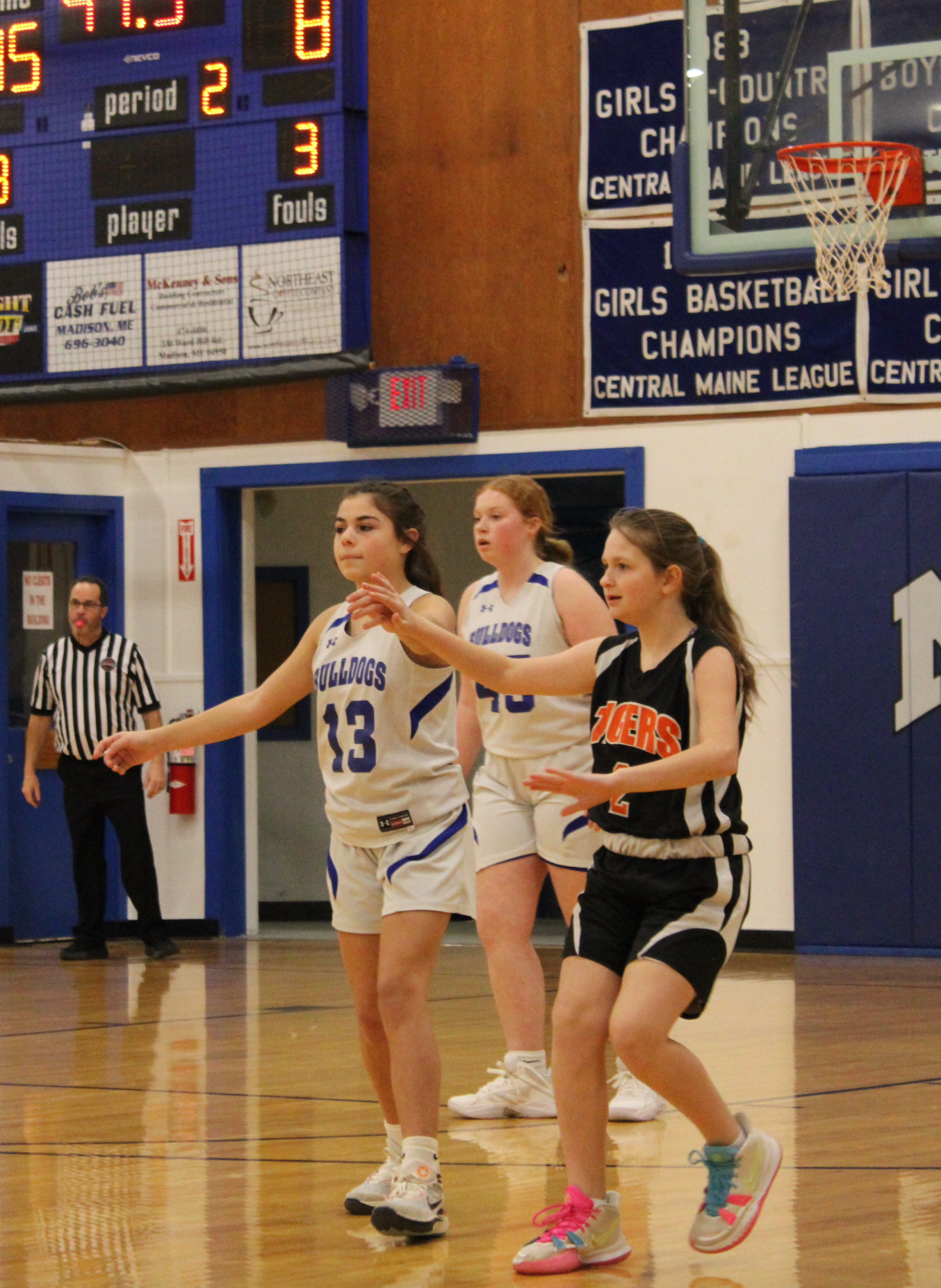 A group of girls playing basketball in front of a scoreboard that says girls basketball champions
