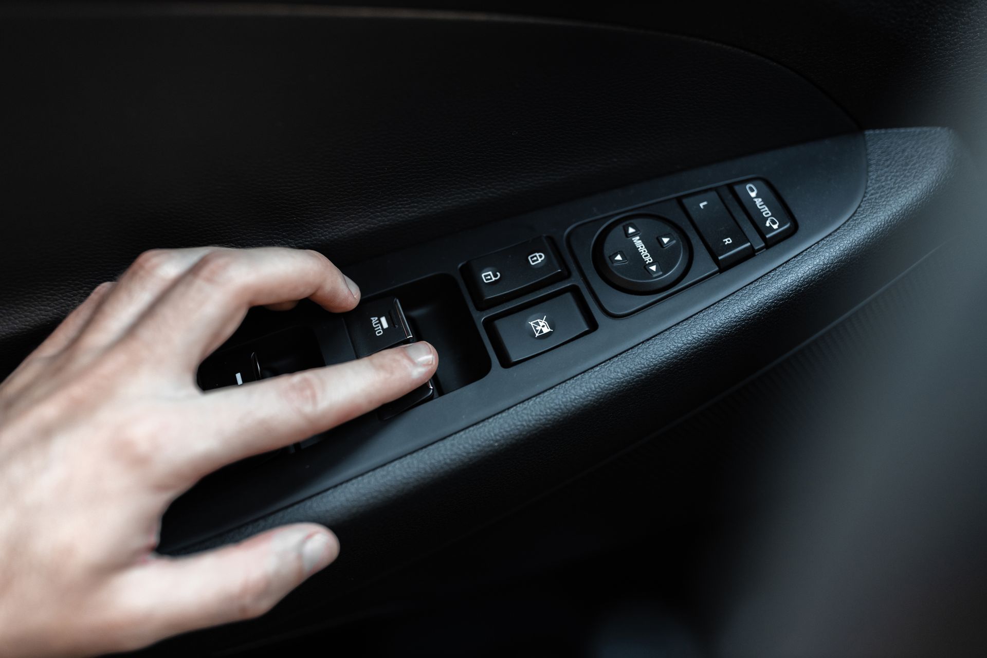 A person is pressing a button on the side of a car door.